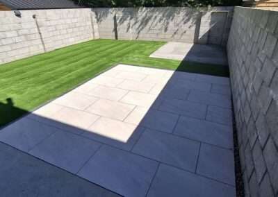 Low maintenance synthetic turf lawn next to paved patio