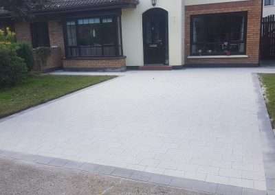 Neatly paved driveway with greenery.